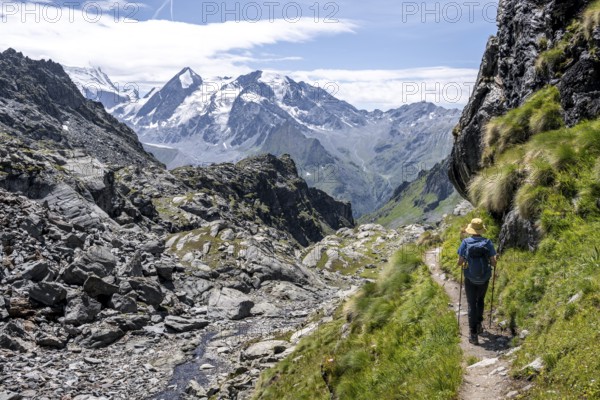 Mountaineer on hiking trail in mountain landscape, descent at Col du Louvie, view of the summit of