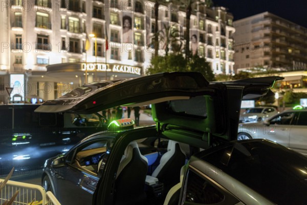 Cannes, France - 23 May 2024: A Tesla taxi stands in front of a hotel on the Promenade de la