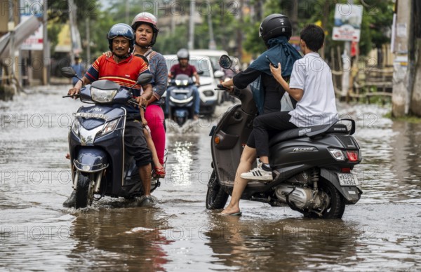 Commuters passing through a waterlogged street following heavy rainfall in Guwahati, India, on 1