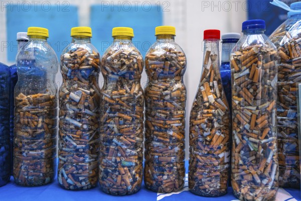 Plastic bottles filled with cigarette butts collected during a beach cleanup highlight