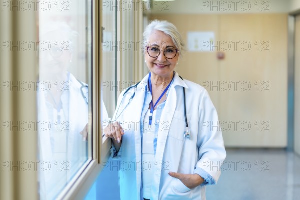 Portrait of a confident senior female doctor standing in a bright hospital corridor, representing
