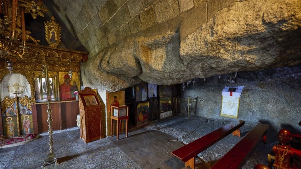Church interior with icons and wooden benches set into a stone wall, Cave of St John, Grotto of