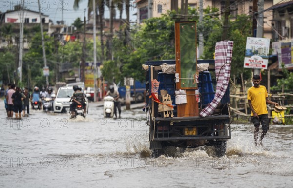 Commuters passing through a waterlogged street following heavy rainfall in Guwahati, India, on 1