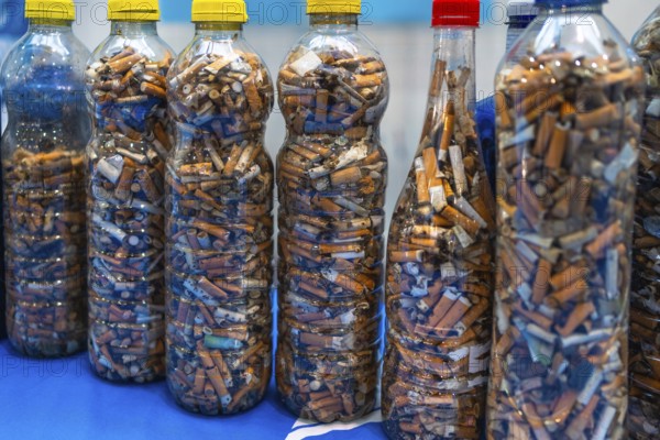 Plastic bottles filled with used cigarette butts highlight the environmental impact of smoking and