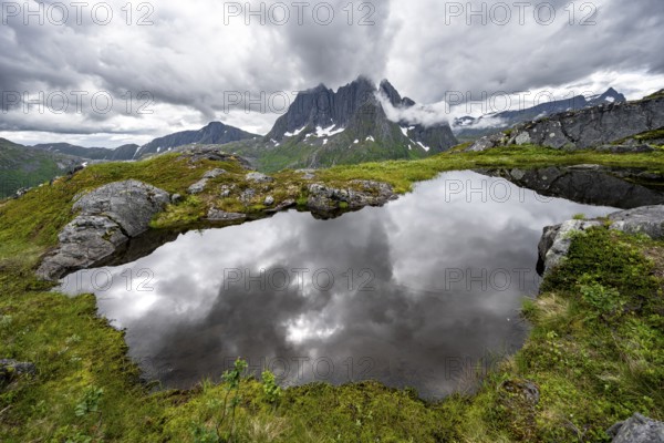 Small lake in mountain landscape, hike to Mount Barden, reflection with mountain peak Breidtind,