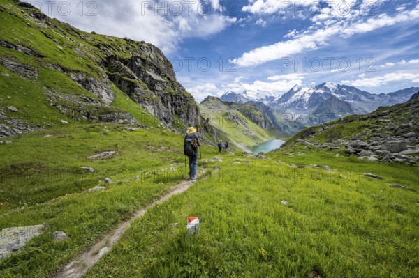 Mountaineer on hiking trail in mountain landscape, descent from Col du Louvie, view of Lac du