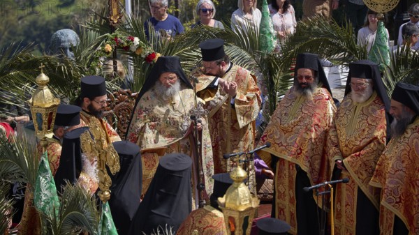 Orthodox priests in splendid robes hold a solemn ceremony with golden elements and palms, Orthodox
