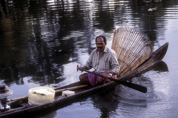 Fisherman with bamboo fishing basket fishing in the backwater of Kuttanad, Kerala, South India,