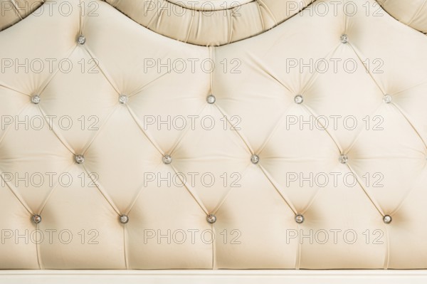 Beige soft textile background with symmetrical buttons on the corners of diamonds. Soft and