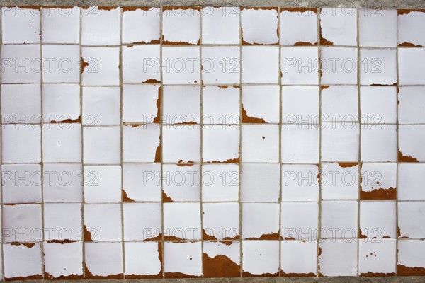 An old white obsolete and damaged tiled wall, good as a texture or background design element