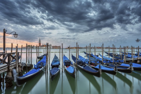 Gondolas on St Mark's Square in Venice, Italy, during a dramatic sunrise, Europe