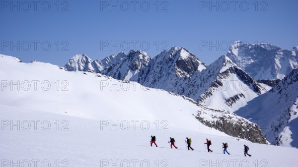 group of backcountry skiers crossing a glacier on their way to a high summit in the Alps of