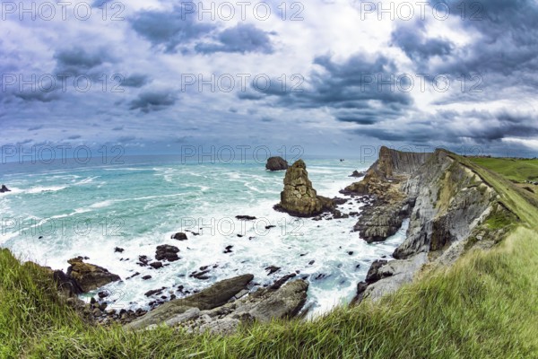 Powerful surf waves with a foam crest. Dramatic stormy sky. Cantabria Beaches, Portio Beach. Windy