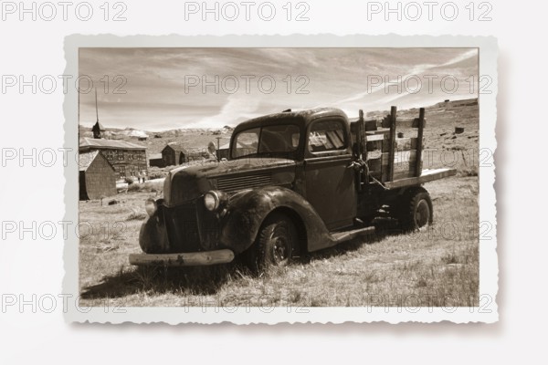 Old lorry rusting in a meadow in the former gold mining town of Bodie. Photo in sepia tone with