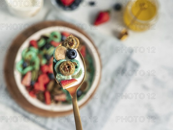 Trendy food - pancake cereal. Bowl of colorful mini cereal pancakes in spoon with milk. Tiny