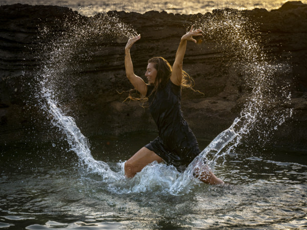 Middle-aged woman dancing and throwing water in the air, Maioris beach, llucmajor, Majorca,