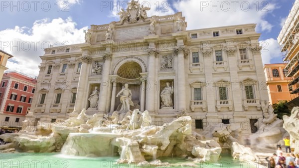 Tourists and people walking next to the Trevi Fountain in a sunny day with clouds, one of the most