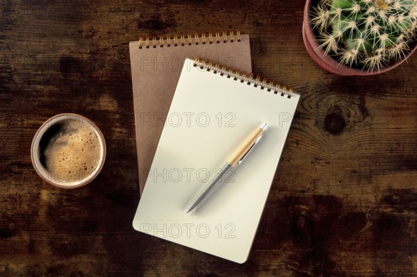 Notebook with a pen, coffee, and plant, overhead flat lay shot on a rustic wooden desk, a mockup,