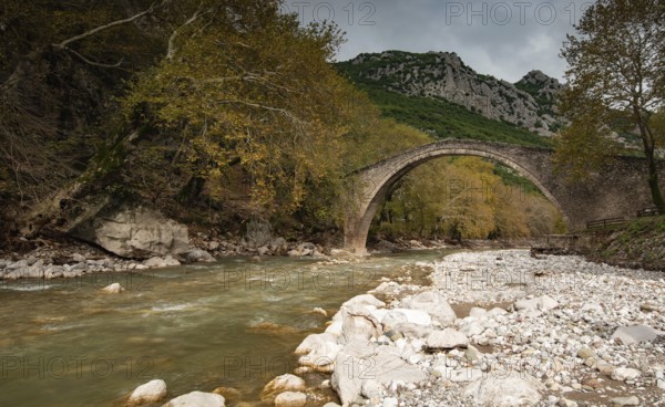 Ancient, stoned, arched bridge St. Vissarion on the Portaikos river in autumn. Trikalla pyli