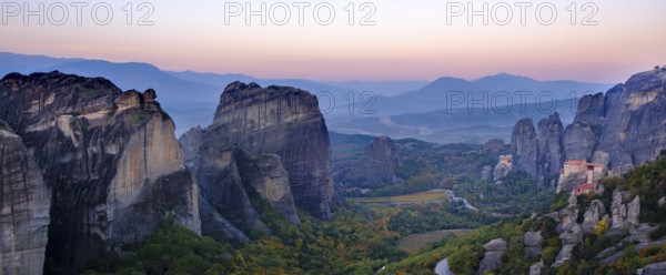 Panoramic view of majestic rock formations and a valley with a monastery at dusk, Meteora valley