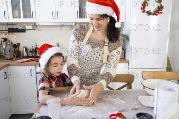 Mom and daughter in the white kitchen are preparing cookies for Christmas and new year. Family day,