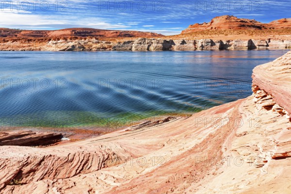 The smooth emerald water of the lake contrasts with the bright red terracotta sandstone shores.