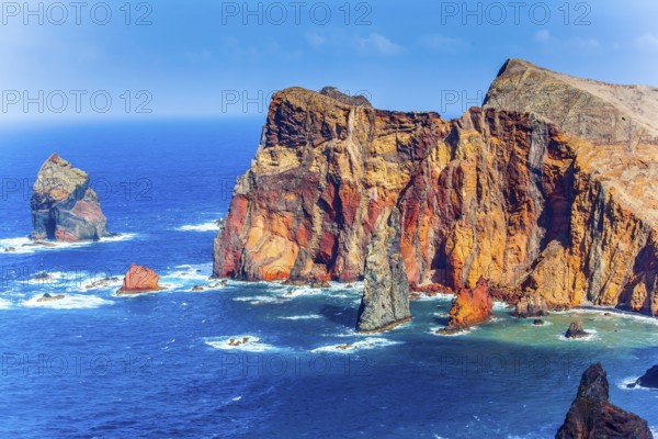 The west coast of the island of Madeira - red rocks, turquoise surf. The blinding midday sun