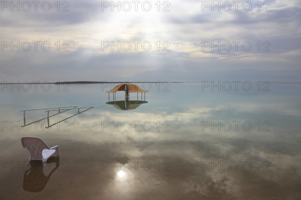 Medical beach on the Dead Sea, Israel. Round gazebo and a beach chair in the water. Cloudy sky
