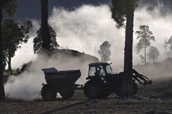 Tractor spreading lime with a fertiliser spreader, West Coast, New Zealand, Oceania