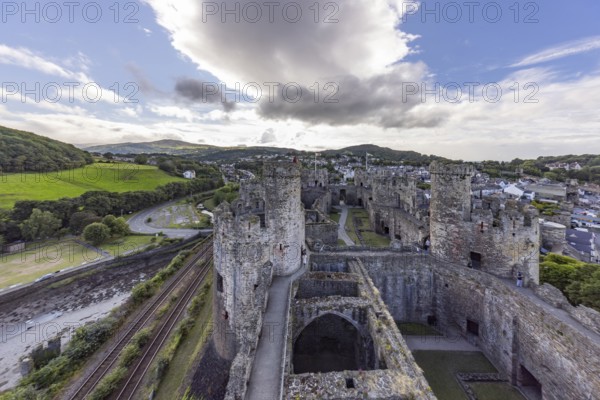 Conwy Castle, medieval castle with towers and surrounding town in a green landscape under a cloudy