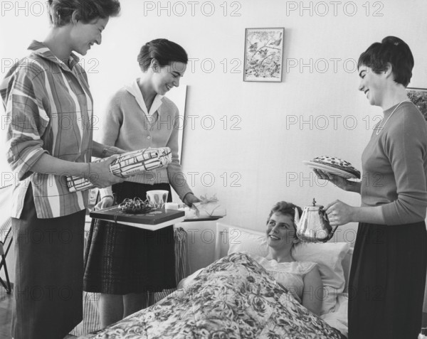 Birthday in the 1960s. A young woman lies in bed and is surprised by her girl friends singing happy