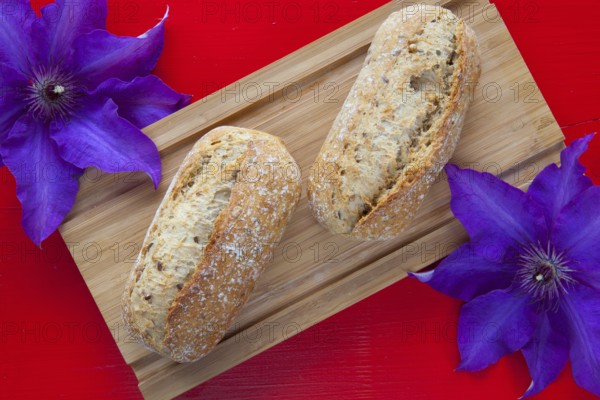 Fragrant breakfast - Two wheat bread and clematis flower on wooden desk