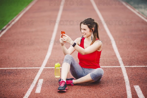 Beautiful fitneß girl uses smartphone at stadium after workout. Sports and healthy. Sport woman use