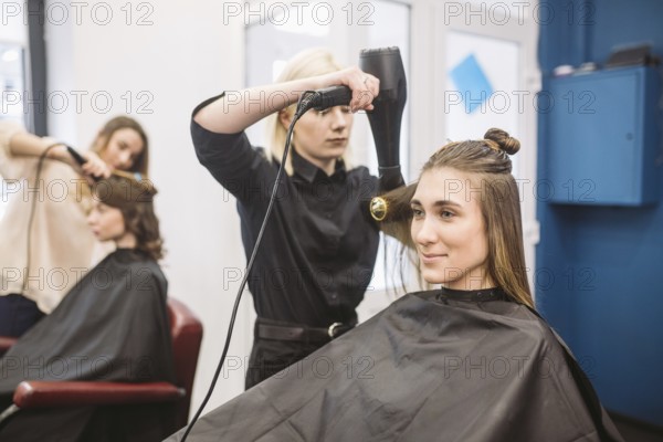 Portrait of happy woman at the hair salon. Professional hair styling concept. Hairdresser drying
