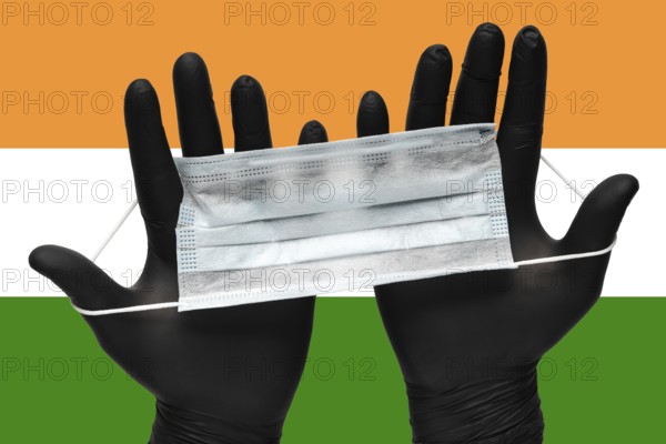 Doctor holds face mask in hands in black medical gloves on background colors National Flag of India