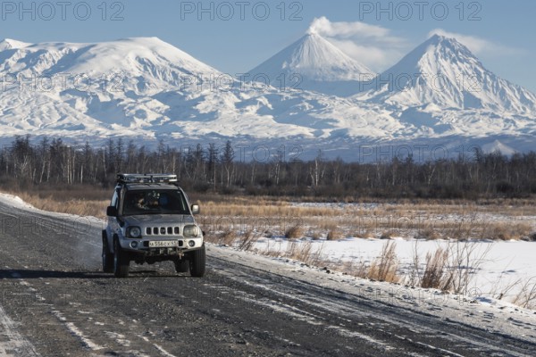 Japanese Sport Utility Vehicle Suzuki Jimny driving along road on background beautiful winter