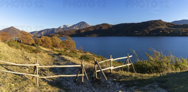A wooden fence and hiking trail on the banks of Campotosto Lake in the mountains of Abruzzo in