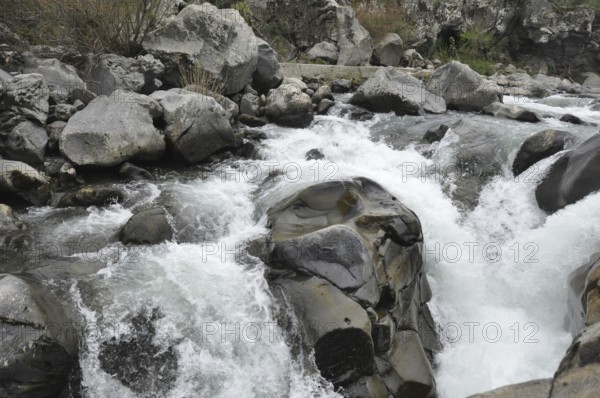 Whitewater rapids swirling around large rocks in a river, The Alcantara Park is located on the