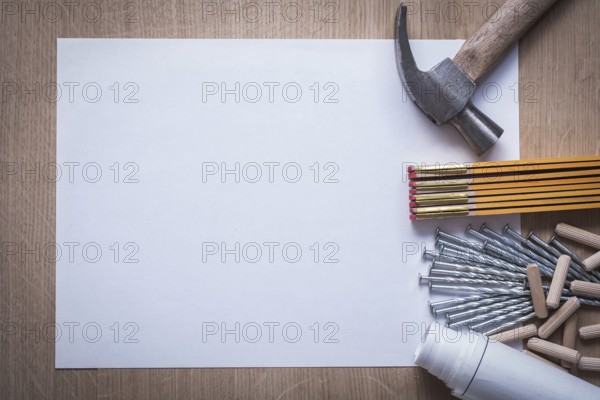 Wooden meter rolled construction plans blank paper metal nails claw hammer heap of fluted dowels on