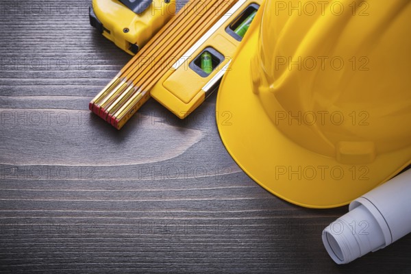Tape-line blueprints construction level hard hat and wooden meter on vintage wood board maintenance