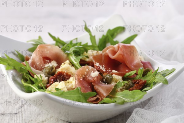 Arugula salad, prosciutto with sun-dried tomatoes, slices of mozzarella, capers, seasoned with