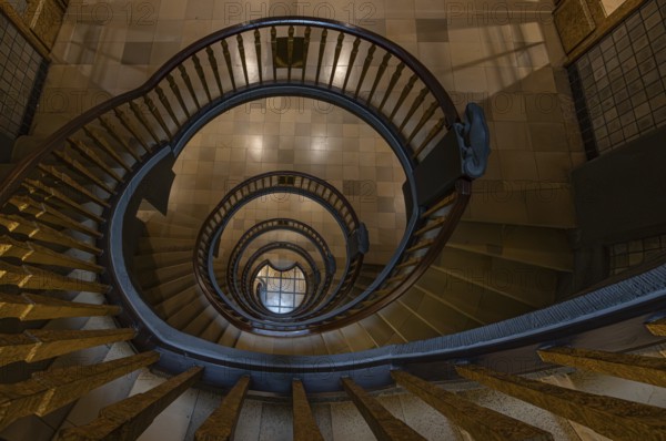 Elegant spiral staircase with wooden railing in a building, abstract view from above,
