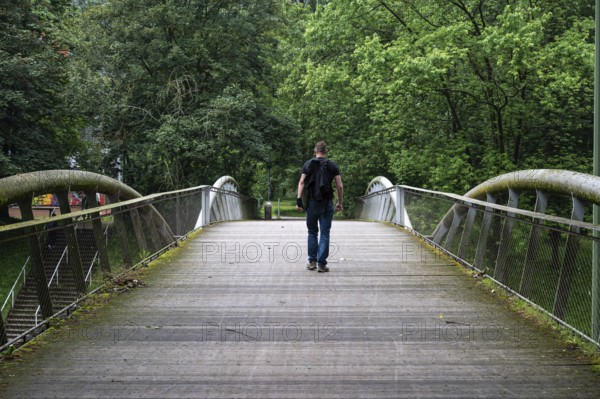 Man walking over a pedestrian bridge at Peterbos, Anderlecht, Brussels Capital Region, Belgium.