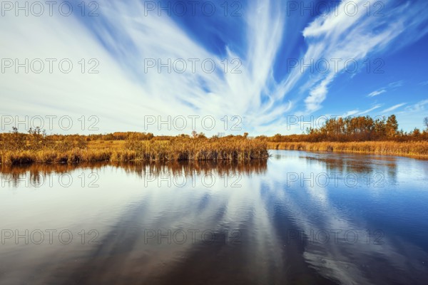 Cirrus clouds are reflected in the Winnipeg River. Wonderful autumn day in Manitoba. Old Pinawa Dam