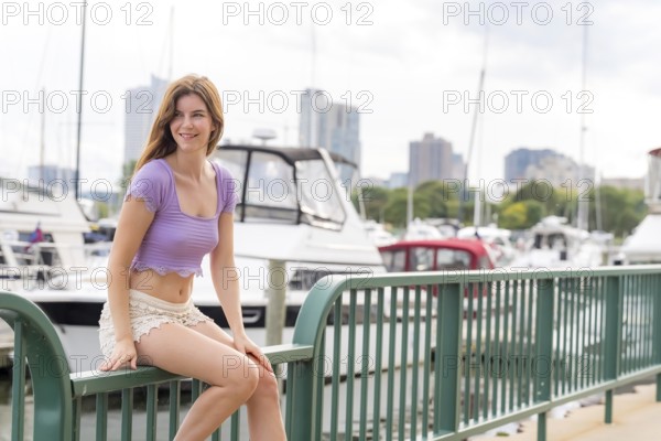 A gorgeous redhead model enjoys the perfect summer weather at a local marina, surrounded by boats