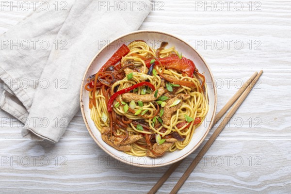 White bowl with Chow Mein or Lo Mein, traditional Chinese stir fry noodles with meat and