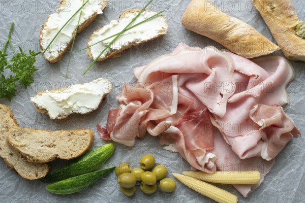 Cold appetizer. Cold cuts. Different snacks on a white crumpled paper, ham, bread, vegetables, from