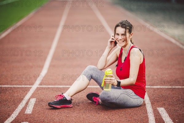 Sport and technology. A beautiful young Caucasian woman with ponytail sitting resting after workout