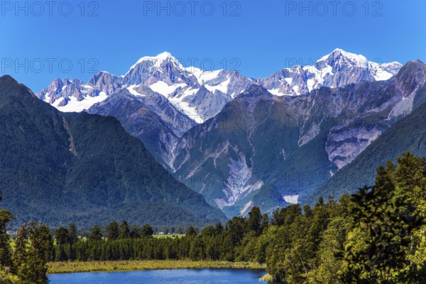 Mountain peaks covered with snow. Mirror glacial Lake Matheson surrounded by mountains Mount Cook