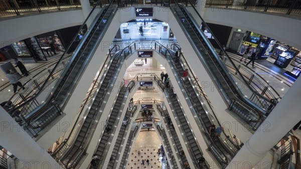 High angle shot of modern multistorey shopping mall. People traffic on the escalators of each floor